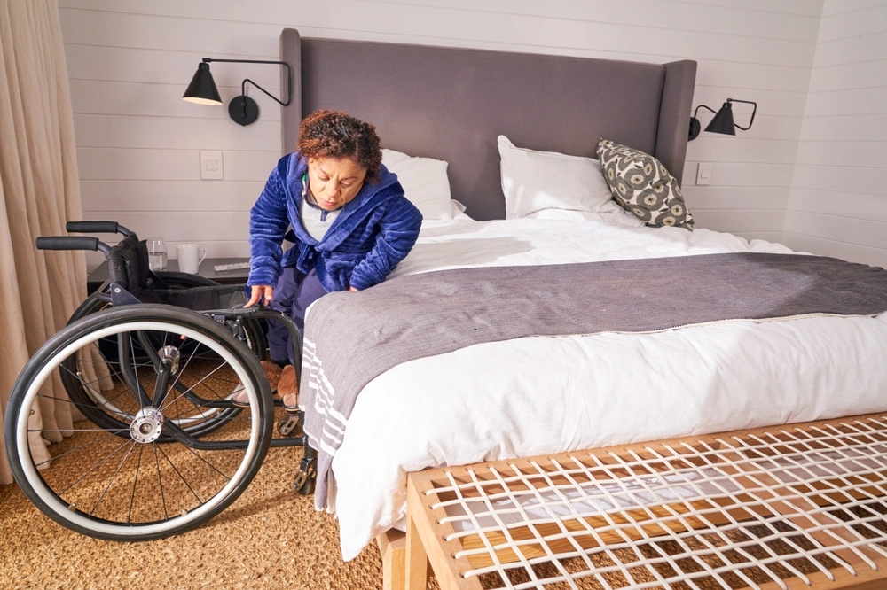 disabled women with dwarfism getting on a wheelchair from bed